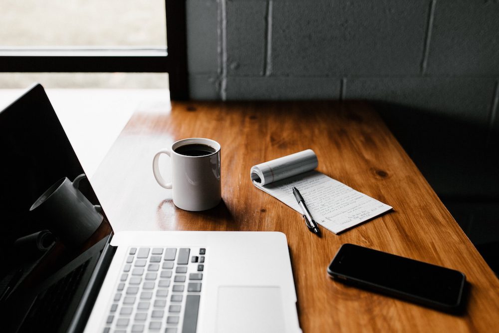 A cup of coffee and laptop on a table.